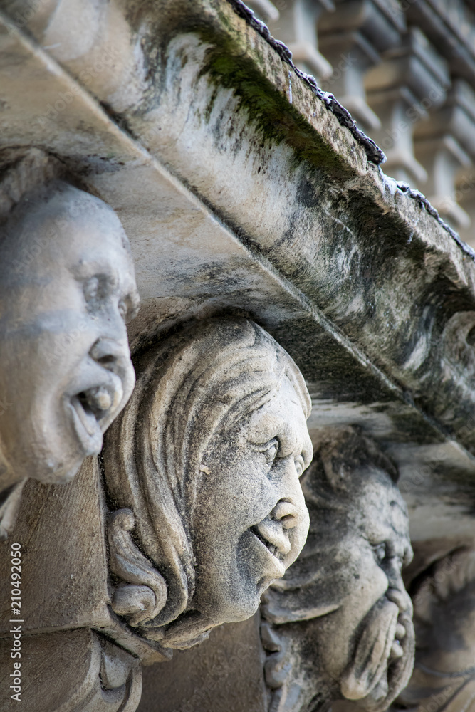 Closeup view of mascarons with funny faces under the balcony of a baroque palace in the province of Syracuse, Sicily