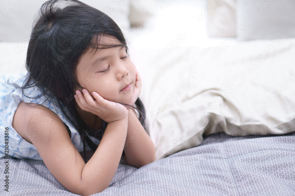 Asian children cute or kid girl sleep or sleepless and hand to cheek for wait and bored or relax with thinking and miss on bed and pillow in room at home with space Asian children cute or kid girl sleep or sleepless and hand to cheek for wait and bored or relax with thinking and miss on bed and pillow in room at home with space