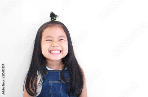 Asian children cute or kid girl and kindergarten student happy smile white teeth and laugh with wear dungarees jean for fashion on white background with space isolated photo