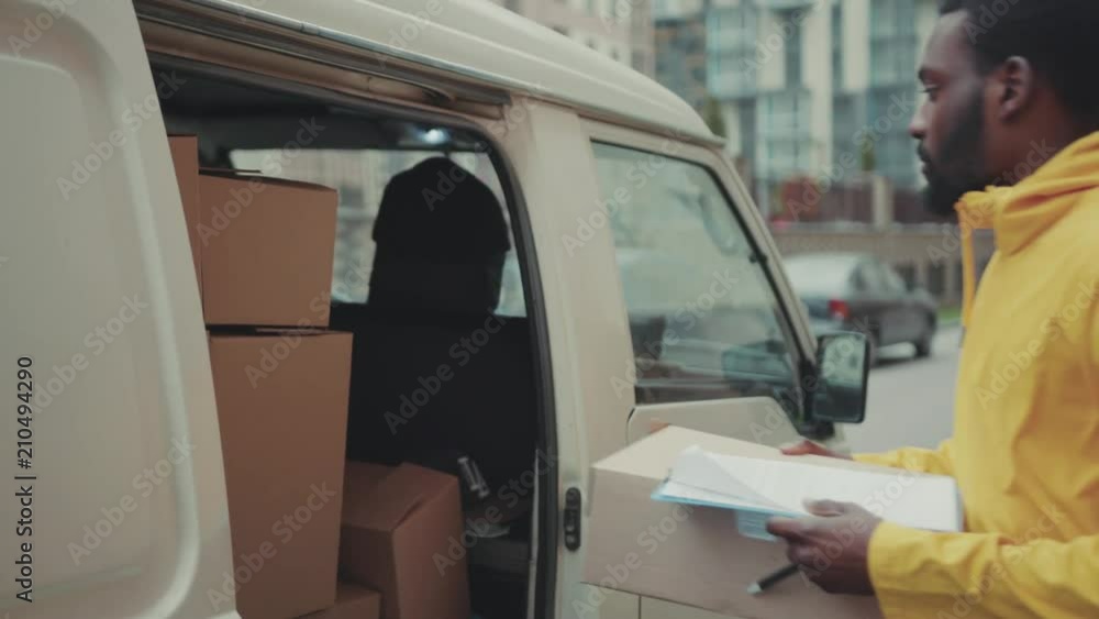 Happy handsome courier young african american man look at camera smile portrait delivery postal uniform job worker cardboard post commercial distribution transport box package logistic service Happy handsome courier young african american man look at camera smile portrait delivery postal uniform job worker cardboard post commercial distribution transport box package logistic service