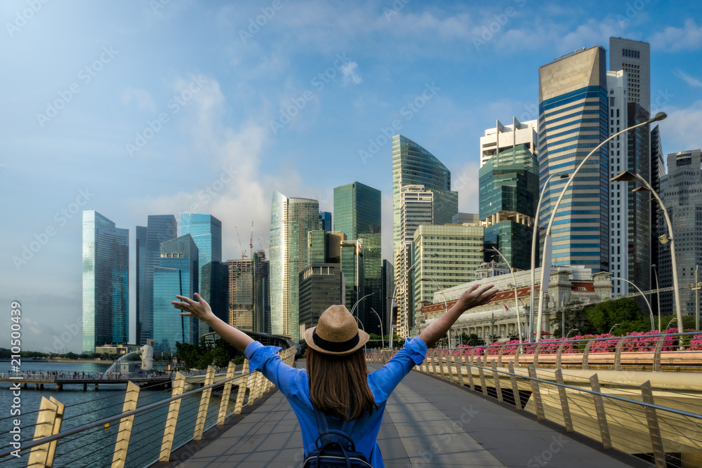 Young woman traveler with backpack and hat traveling into singapore city downtown. Travelling in Singapore concept - obrazy, fototapety, plakaty 