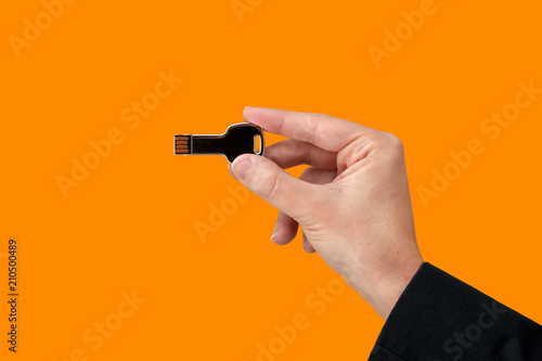 Key USB pen drive on hand with isolated orange background