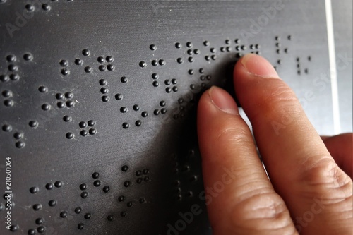 Close up of male hand reading braille text
 photo