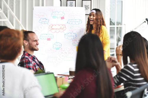 Young Asian businesswoman giving joyful presentation on business plans to colleagues at office