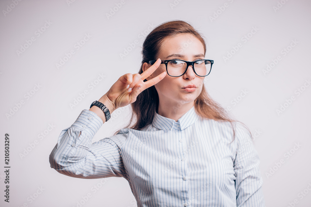 Beautiful business woman with glasses shows a victory gesture near the eyes, copy space