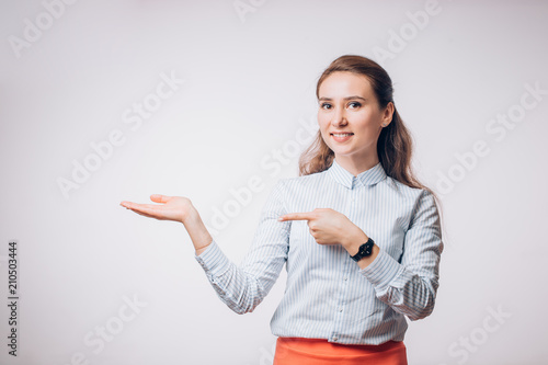 Young brunette business woman presents the product, shows her hand to the empty space,
