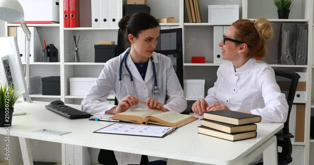 two female doctors talking in light workplace. two female doctors talking in light workplace.