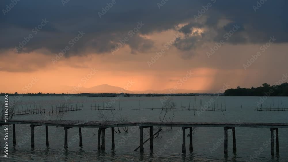 Approaching storm cloud with rain over the sea during sunrise Approaching storm cloud with rain over the sea during sunrise