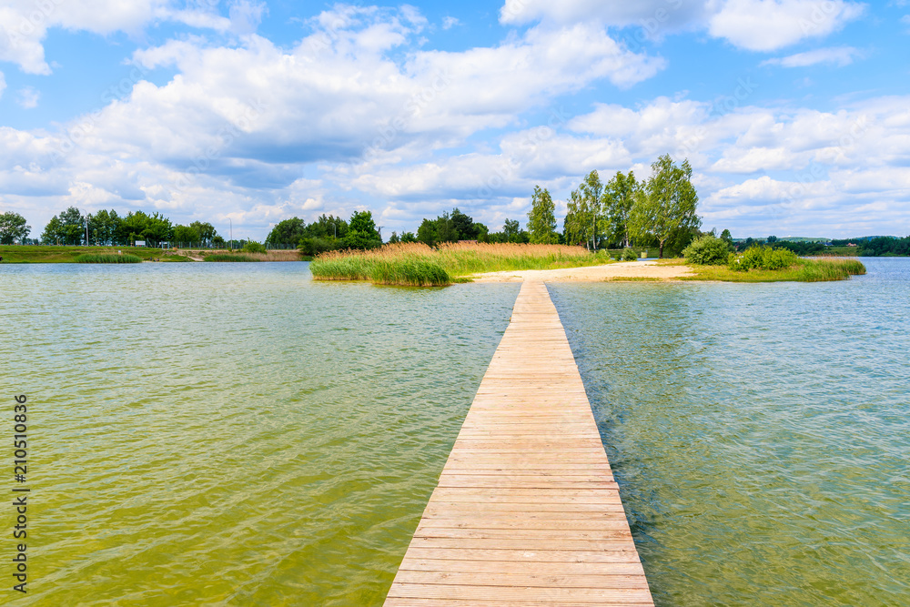 Wooden pier on beach at Kryspinow lake near Cracow city on sunny beautiful summer day, Poland