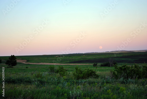Field on horizon, blue sky and harvest moon rising, Ukraine in spring