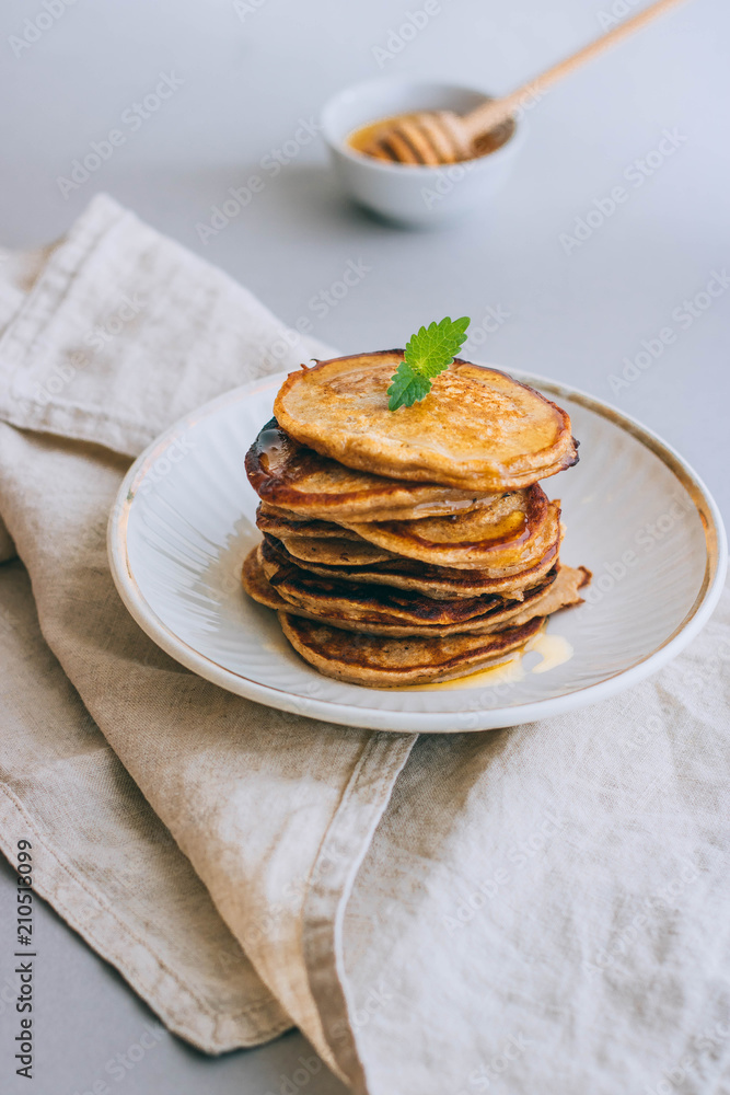 Banana pancakes with walnuts and cedar nuts, honey and mint, honey dipper on a white background. Morning breakfast Banana pancakes with walnuts and cedar nuts, honey and mint, honey dipper on a white background. Morning breakfast