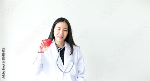 Portrait of smiling female doctor with red heart. Friendly young woman doctor with a stethoscope around on neck. asia.