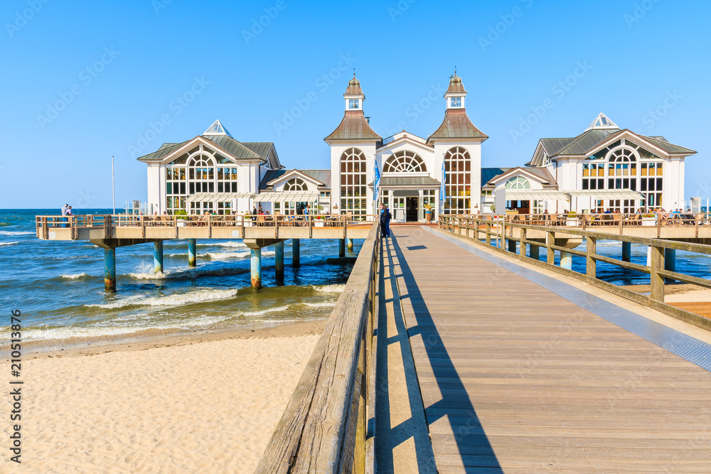 Fototapeta premium View of pier with historic building on sandy beach in Ostseebad Sellin, Ruegen island, Baltic Sea, Germany