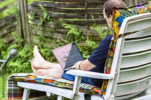 Man working from home in the garden using smart phone and notebook computer