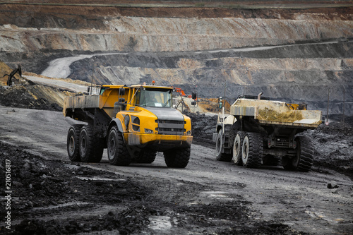 Two heavy articulated dump trucks go to a meeting on the working road.
