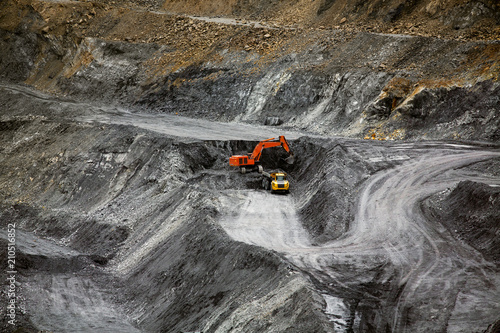 Excavator loads coal in a mining dump truck. Heavy mining industry.