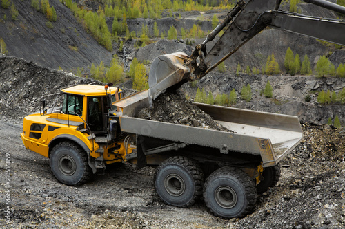 Excavator loads coal in a articulated dump truck. Heavy mining industry.