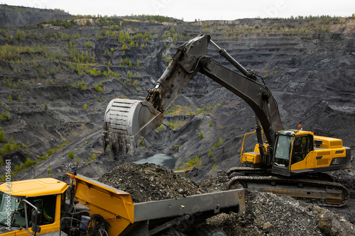 Excavator loads coal in a articulated dump truck. Heavy mining industry.