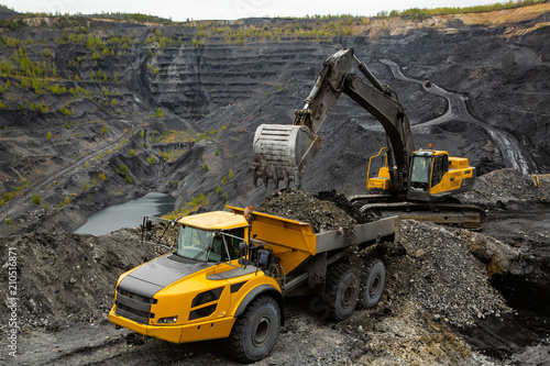 Excavator loads coal in a articulated dump truck. Heavy mining industry.