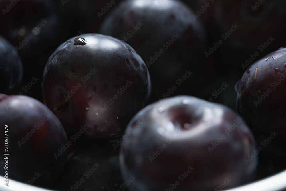 Fototapeta premium closeup of freshly washed big plums in a steel bowl
