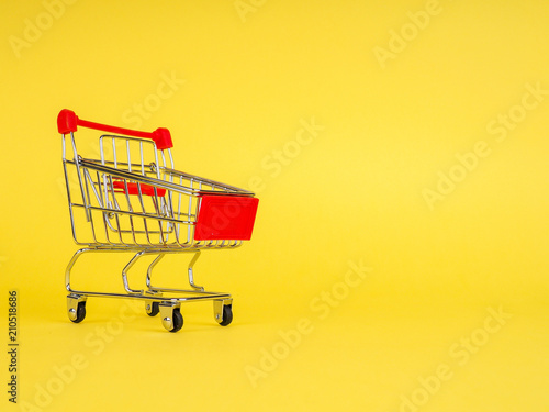 supermarket trolley on yellow background, empty, Concept of shopping. Copy space for advertisement.
