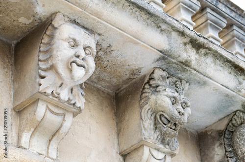 Closeup view of mascarons with funny faces under the balcony of a baroque palace in the province of Syracuse, Sicily