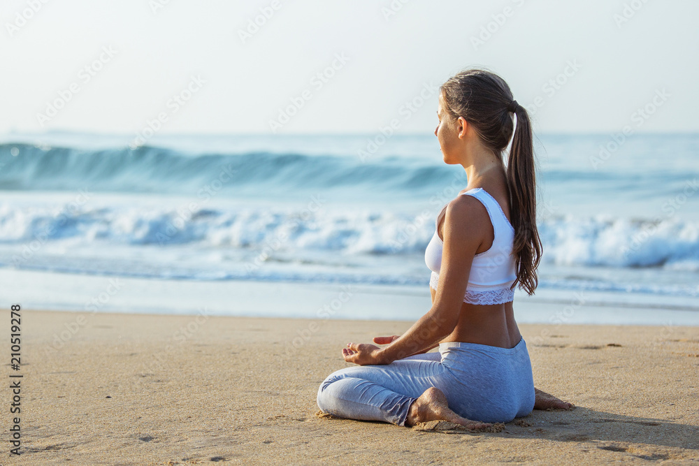 Caucasian woman practicing yoga at seashore of tropic ocean Caucasian woman practicing yoga at seashore of tropic ocean