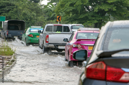 Fototapeta Naklejka Na Ścianę i Meble -  A line of cars ride on a road under water. Flood on the street.