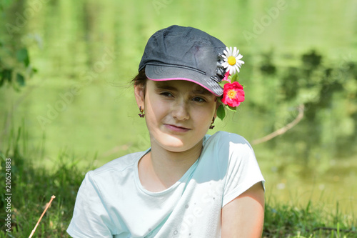 Happy girl in flower garden portrait with decorative flower in cap