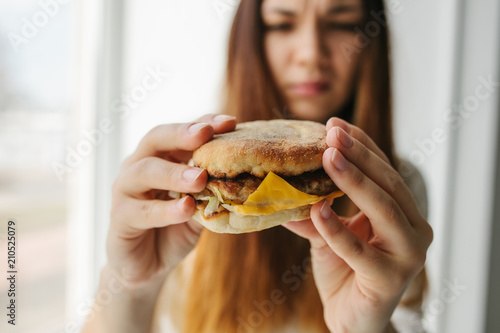 A young girl shows that she does not like a burger. Conceptual image of refusal from unhealthy eating.