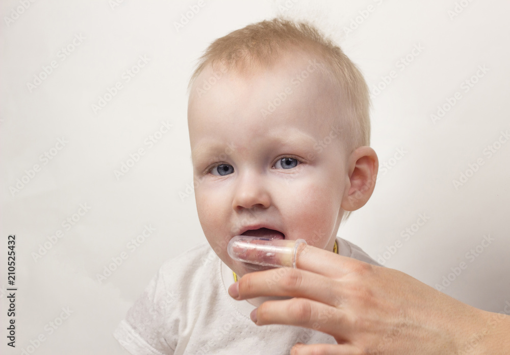 Mother cleans teeth for her little daughter, white background, close-up Mother cleans teeth for her little daughter, white background, close-up