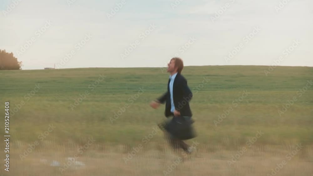 Happy businessman running across a wheat field, waving a briefcase. Happy businessman running across a wheat field, waving a briefcase.