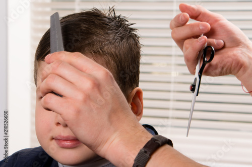 the hairdresser combs the boy and does a hairdo