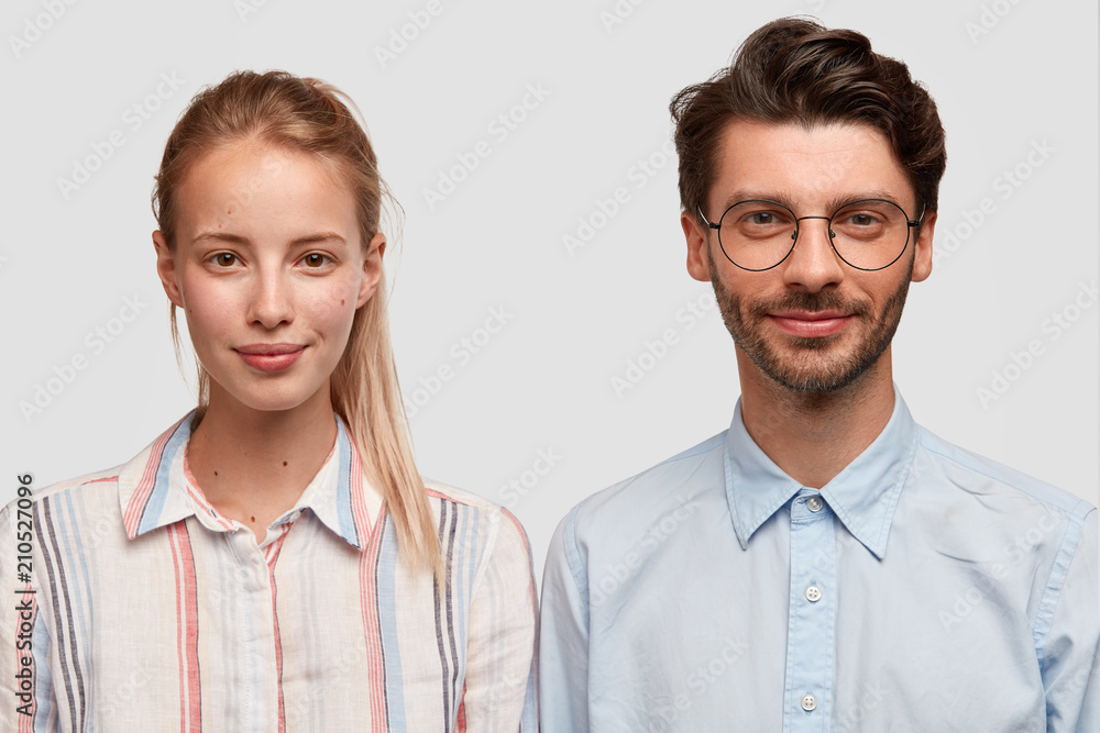 Horizontal shot of pleased classmates pose for making photo, has appealing appearance, dressed in casual clothes, stand next to each other, isolated on white wall. Friendship, relationship concept Horizontal shot of pleased classmates pose for making photo, has appealing appearance, dressed in casual clothes, stand next to each other, isolated on white wall. Friendship, relationship concept