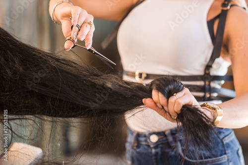 Female hairdresser hold in hand lock of hair, scissors closeup. Keratin restoration, latest trend, fresh idea, haircut picking, shorten tips