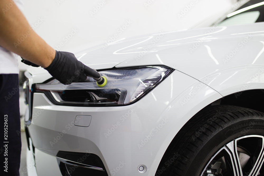 Car detailing - Worker with orbital polisher in auto repair shop. Selective focus. Car detailing - Worker with orbital polisher in auto repair shop. Selective focus.