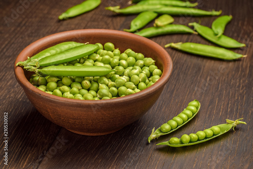 Harvest of freshly picked green peas in a bowl on a wooden rustic table