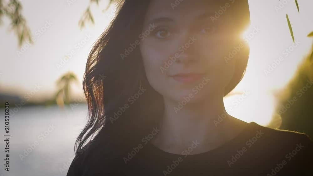 portrait of young pretty brunette woman on a sunset background on a lake portrait of young pretty brunette woman on a sunset background on a lake