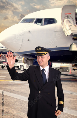 pilot in uniform at the airport waving to service