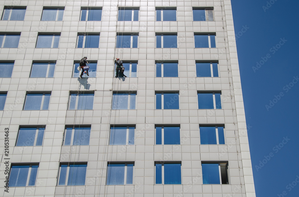 two workers wash the windows on a high-rise building