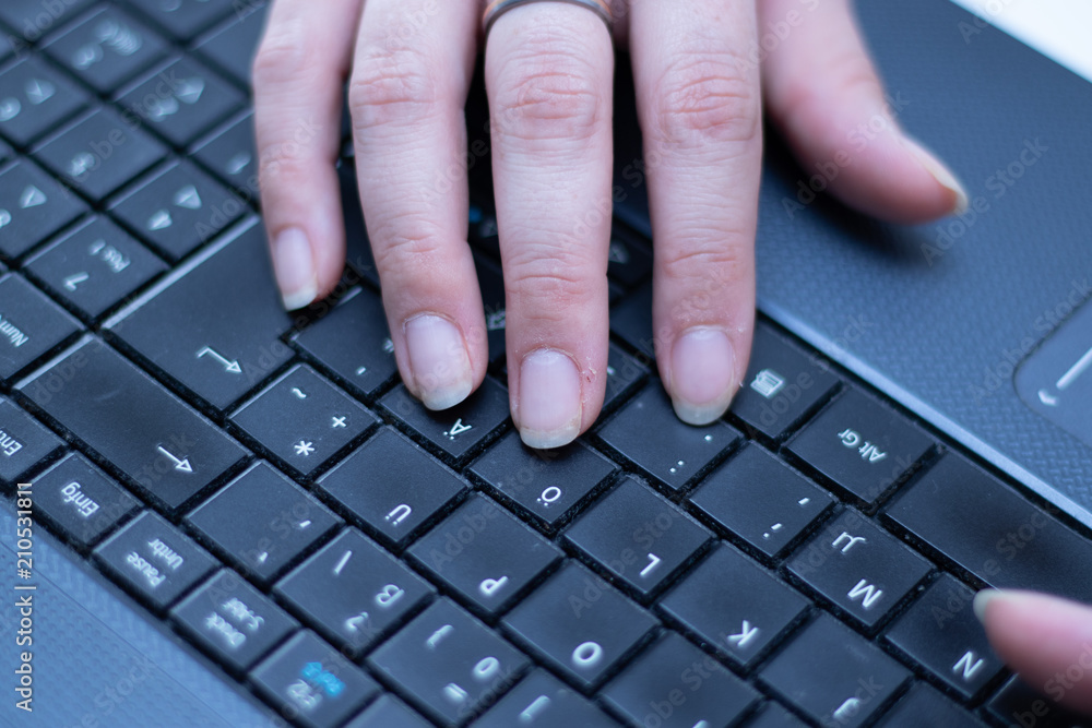 Hand of a woman typing on the keyboard of a computer in the office Hand of a woman typing on the keyboard of a computer in the office
