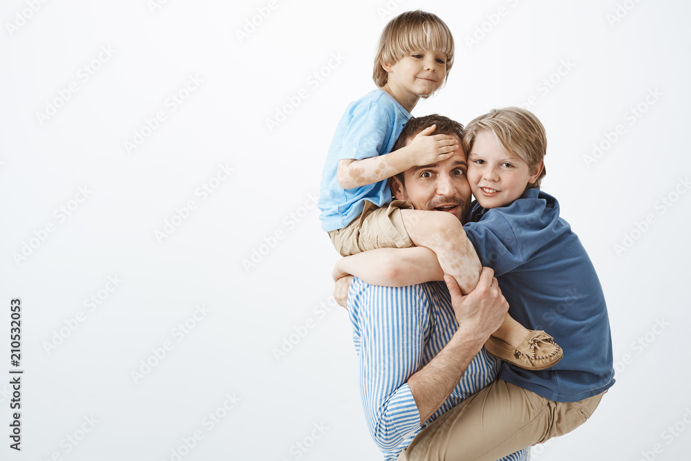 Cute positive family feeling great while playing together in park. Portrait of happy good-looking single father holding son with vitiligo on shoulders and older sibling on chest, fooling around Cute positive family feeling great while playing together in park. Portrait of happy good-looking single father holding son with vitiligo on shoulders and older sibling on chest, fooling around