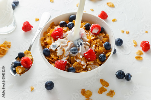 Obraz na płótnie Healthy Morning Breakfast honey Corn flakes with fresh fruits of Raspberry, blueberries and pouring milk in bowl