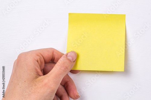 A female hand holds an empty sticker post-it for writing notes or ideas.