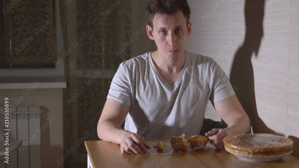 Man in the kitchen eating a bun at night. Man in the kitchen eating a bun at night.