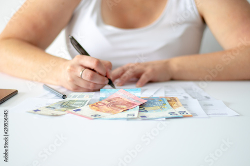 Businesswoman sitting behind her desk and some different euro banknotes lying in front of her 