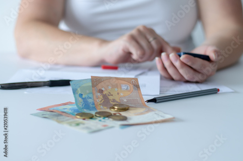 Woman using a calculator behind cash money lying on her desk in the office