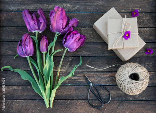 Purple parrot tulips and craft gift box on rustic wooden background, Valentines Day or Mothers day background, top view. Gift box, ball of jute, flowers and retro scissors - set for gift wrapping. #210539624