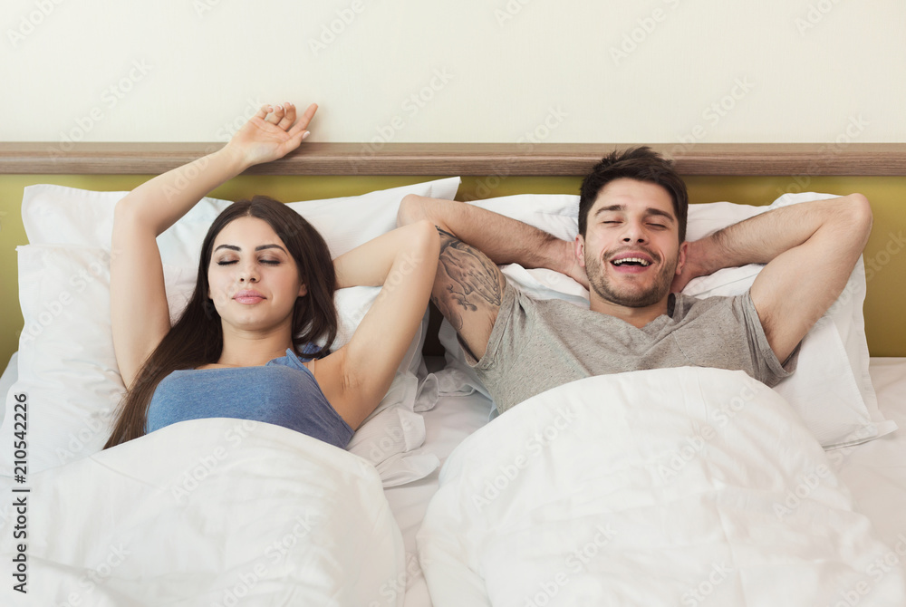 Happy young couple waking up in the morning on bed Happy young couple waking up in the morning on bed