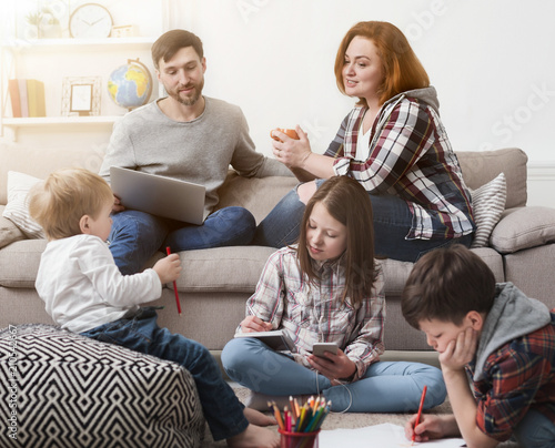 Children playing on the floor while parents on sofa